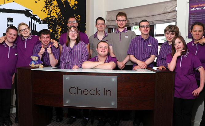 group-of-smiling-premier-inn-colleagues-posing-by-check-in_force-for-good